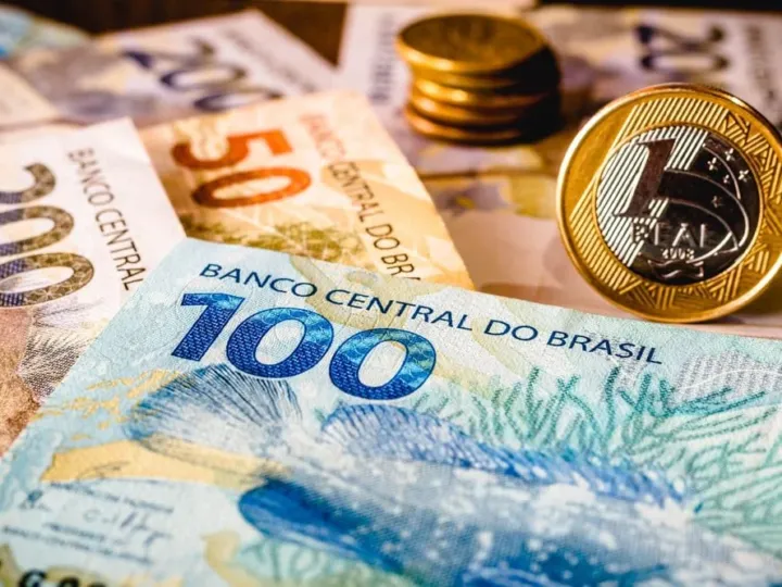 Mão segurando cédulas de real, simbolizando renda ou pagamento em dinheiro