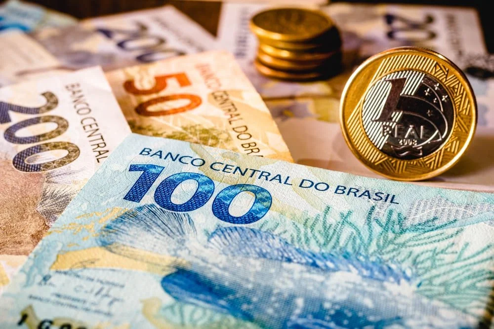 Mão segurando cédulas de real, simbolizando renda ou pagamento em dinheiro