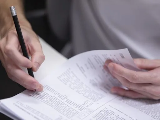 A imagem mostra as mão de uma pessoa segurando uma caneta ao realizar uma prova