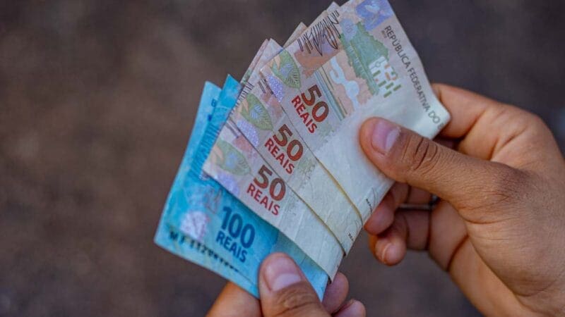 Foto de uma pessoa com notas de 100 e 50 reais na mão