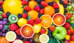 Frutas como laranja, limão, morango, kiwi, maçã verde e uva dispostas coloridamente em uma mesa
