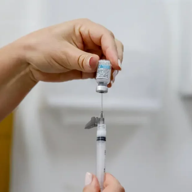 Profissional de saúde manuseando seringa com vacina meningocócica ACWY