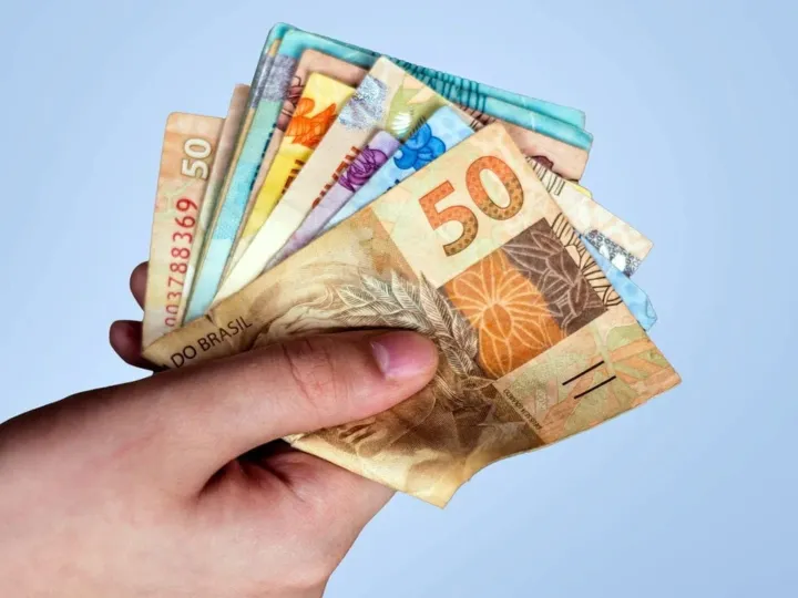 Notas de real e moedas empilhadas representando economia e finanças no Brasil
