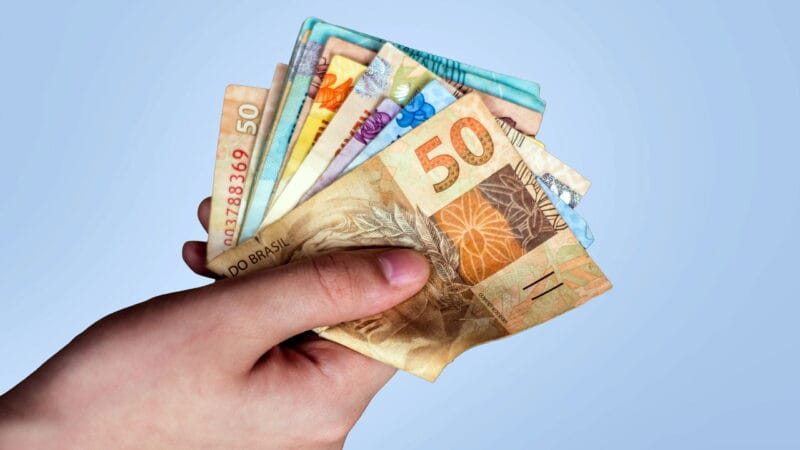 Notas de real e moedas empilhadas representando economia e finanças no Brasil