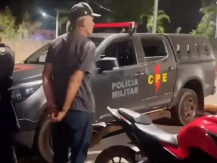 homem algemado de costas próximo a uma viatura da CPE e uma moto vermelha
