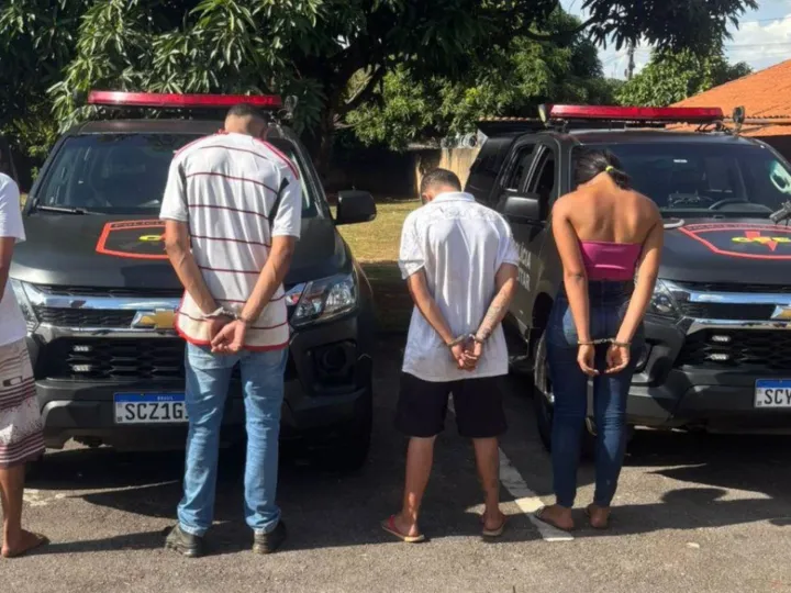 Imagem dos presos algemados em frente a viaturas da policia especializada