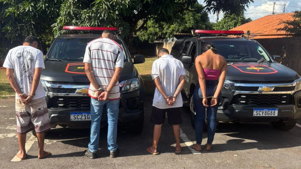 Imagem dos presos algemados em frente a viaturas da policia especializada