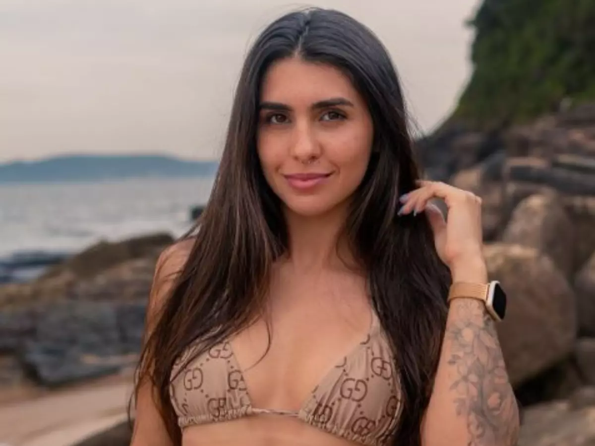 Sabrina Saraiva em biquíni bege à beira da praia, sorrindo para a câmera