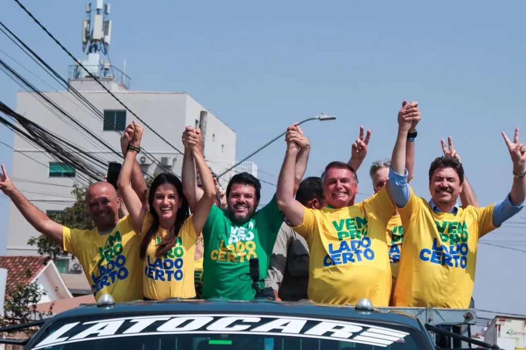 Jair Bolsonaro, Márcio Corrêa e aliados políticos em cima de um veículo, com camisetas amarelas e verdes com os dizeres "Vem pro lado certo", durante uma carreata em Anápolis.