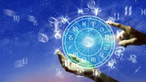 Mãos humanas apontando para um círculo com os doze signos do zodíaco, em um fundo de céu estrelado.