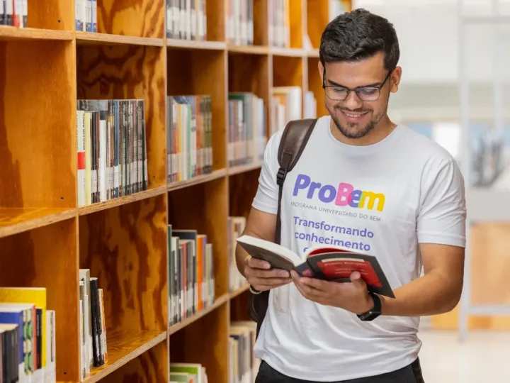 Estudante olhando livro dentro de uma biblioteca