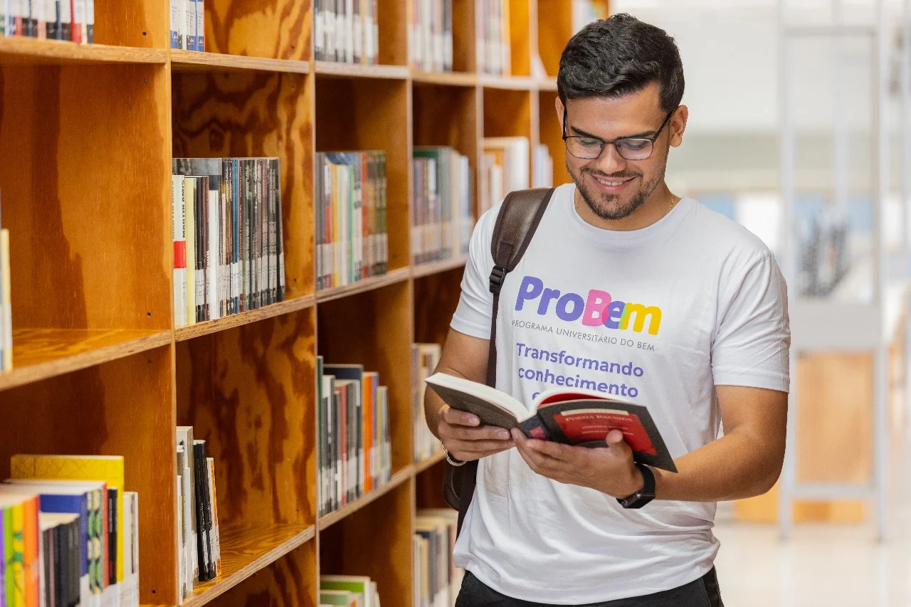 Estudante olhando livro dentro de uma biblioteca