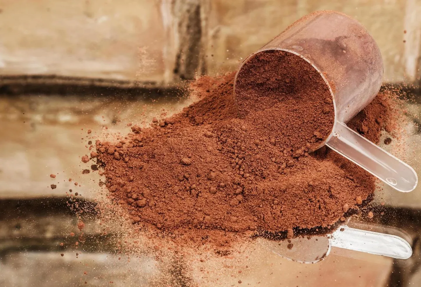 Suplemento em pó de cor achocolatada derramado com colher medidora transparente