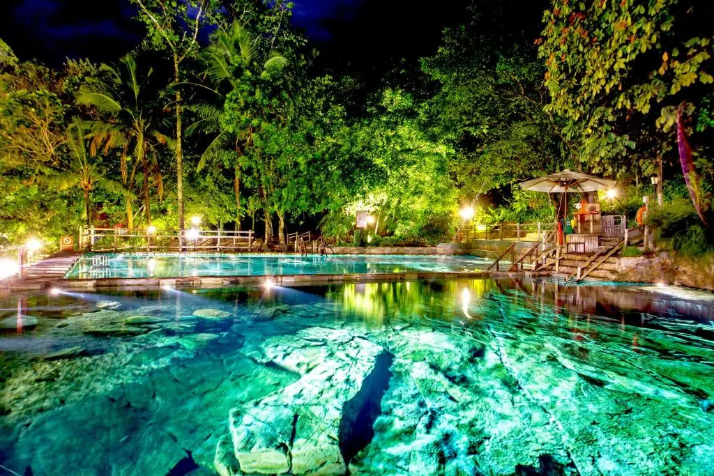 Piscina iluminada à noite em meio à vegetação no Rio Quente Resorts