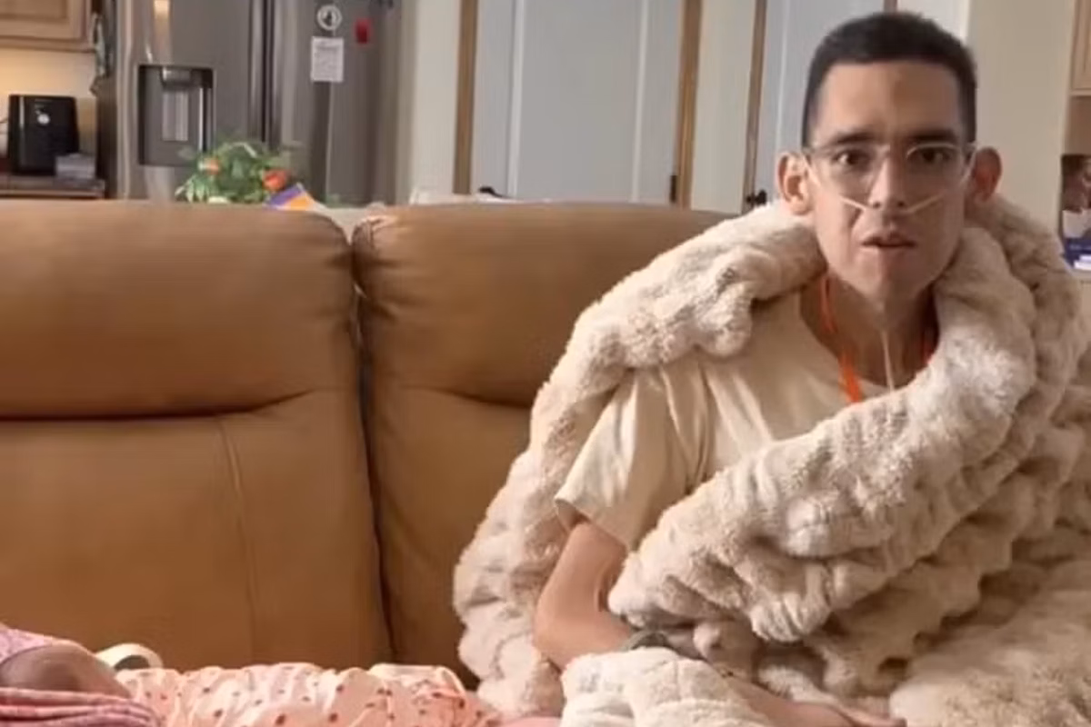 Influencer Tanner Martin com expressão de medo e corpo abatido sentado em sofá