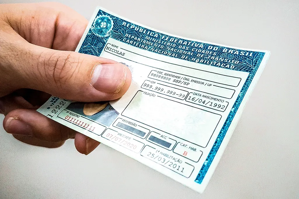 Pessoa segurando o novo modelo da CNH com fundo desfocado.