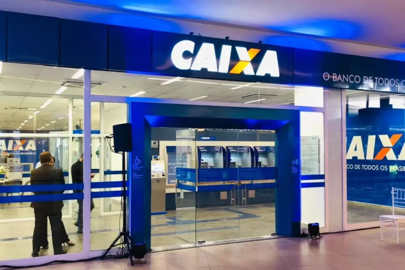 Entrada de agência da Caixa Econômica Federal com fachada moderna e letreiro iluminado