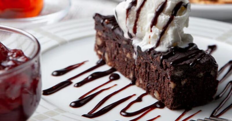 um pedaço de bolo com sorvete e calda em um prato de sobremesa