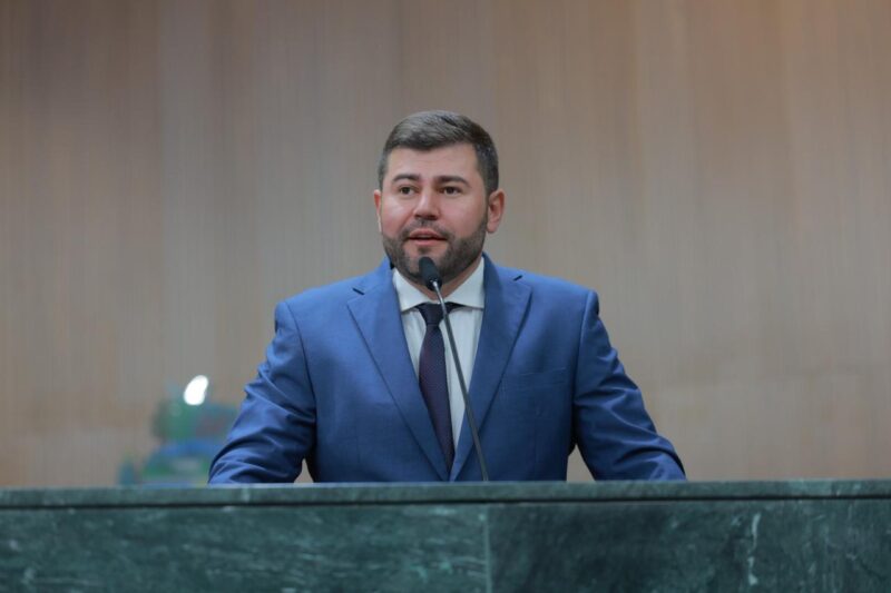 O deputado estadual Amilton Filho discursa na tribuna, usando terno azul e gravata escura, em um ambiente institucional.