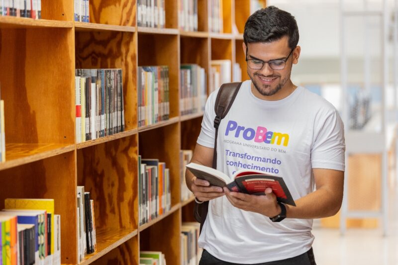 Estudante olhando livro dentro de uma biblioteca