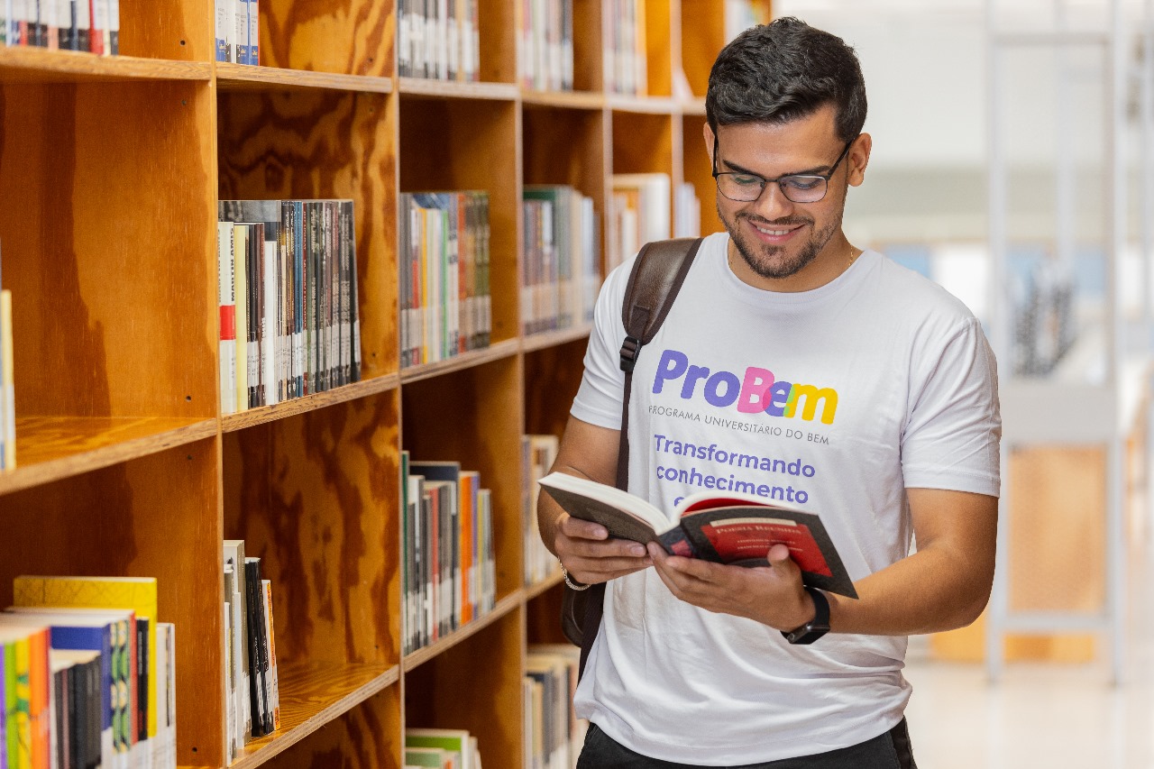 Estudante olhando livro dentro de uma biblioteca