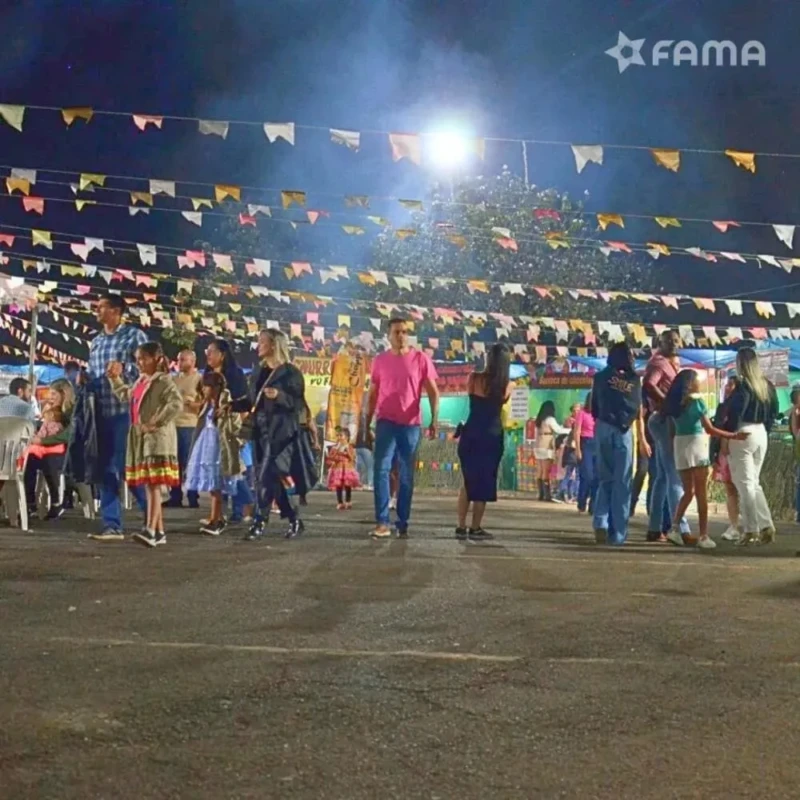 Pessoas participam da festa junina Arraiá BAAN 2024 com decoração típica e barracas temáticas