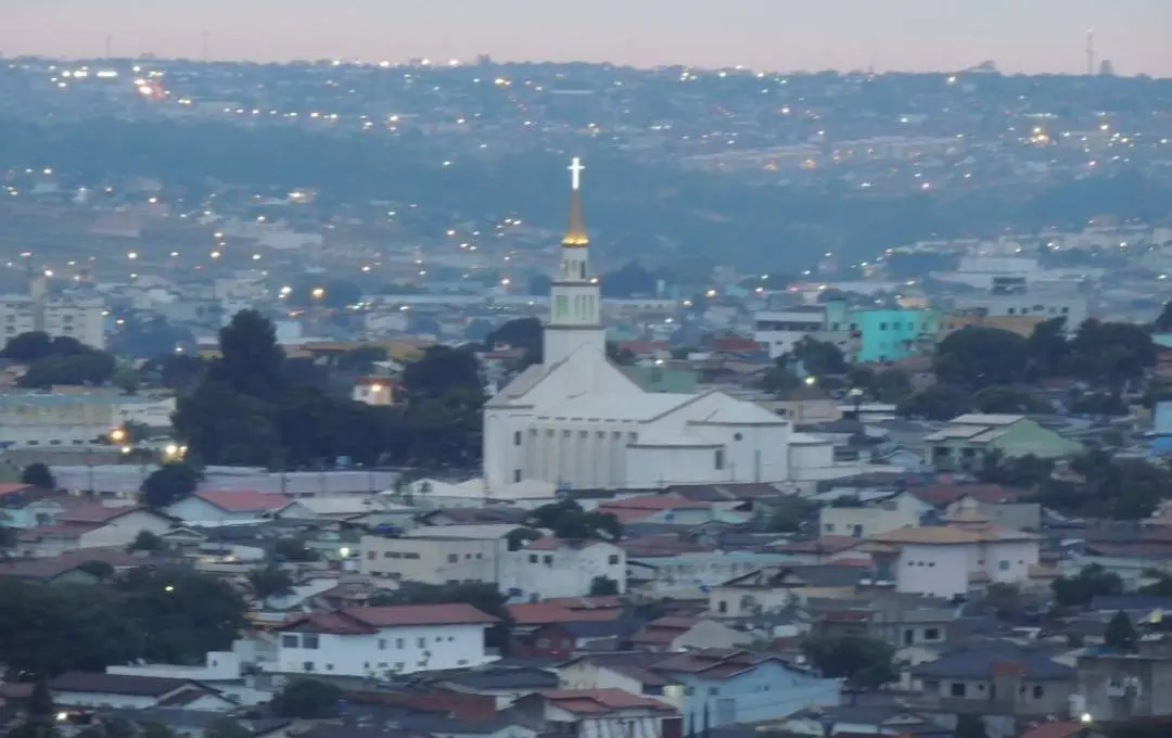 Vista panorâmica de Anápolis com igreja iluminada ao entardecer.