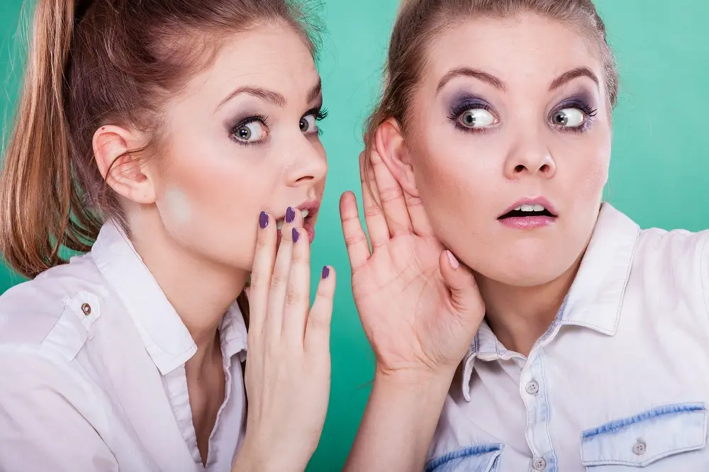 Mulheres trocando confidências com expressão surpresa e curiosidade