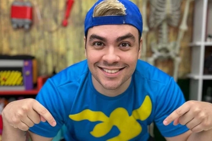  Luccas Neto com boné azul e camiseta estampada posa sorridente para ensaio promocional