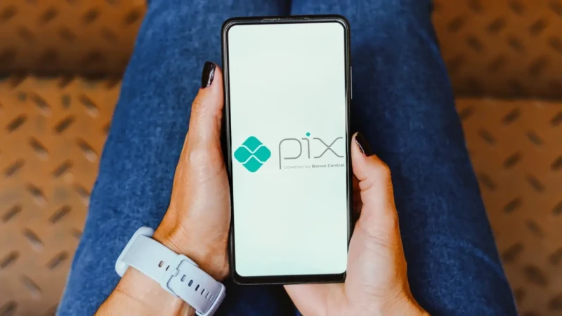 Pessoa segurando um celular exibindo a tela inicial do Pix, sistema de pagamentos do Banco Central.