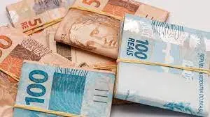 Maços de cédulas de 100 e 50 reais presos com elásticos.