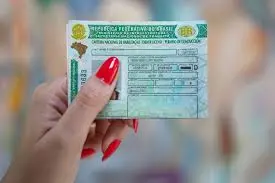 Mulher segurando a CNH brasileira com unhas pintadas de vermelho

