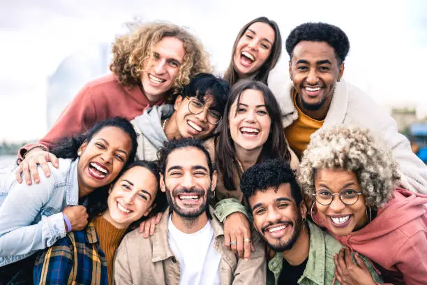 Jovens sorridentes posam juntos para foto em grupo, mostrando diversidade e amizade.