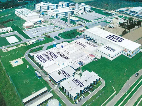 Vista aérea do parque industrial do Laboratório Teuto em Anápolis, com vários prédios identificados com a marca.

