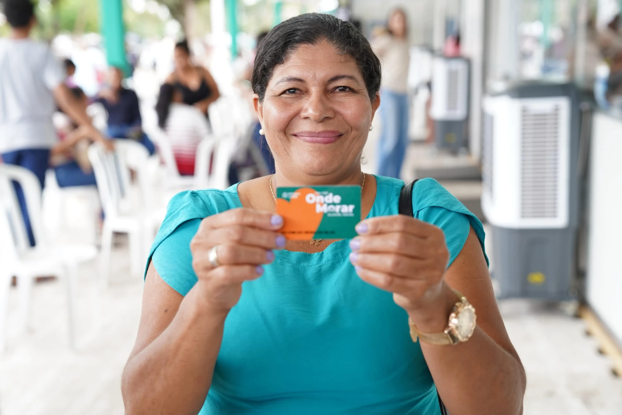 Mulher sorridente segura o cartão do programa Onde Morar em Anápolis.