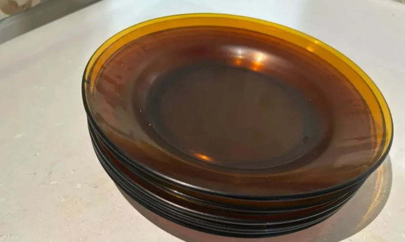 Conjunto de pratos de vidro âmbar Duralex empilhados sobre bancada clara