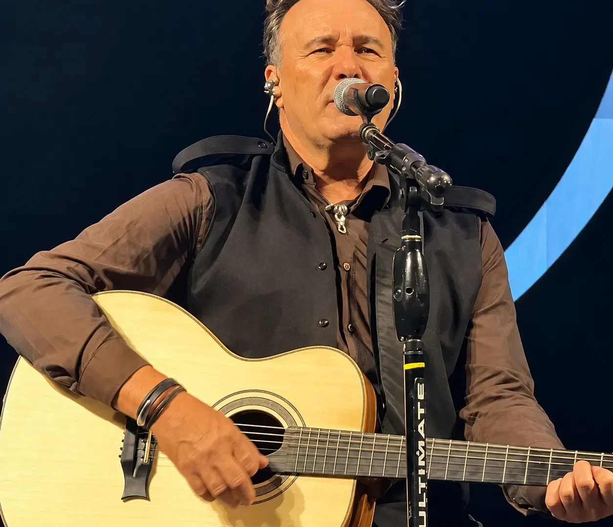 Cantor Paraná se apresenta no palco com violão durante show.