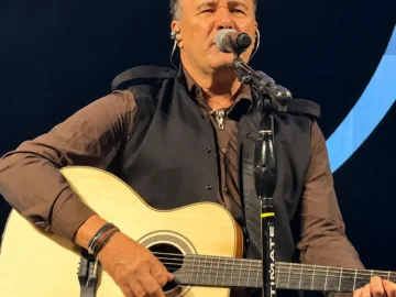 Cantor Paraná se apresenta no palco com violão durante show.