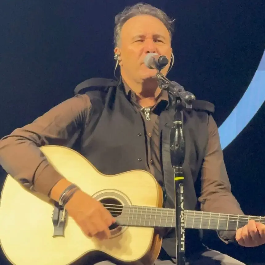 Cantor Paraná se apresenta no palco com violão durante show.
