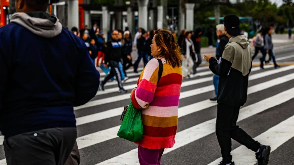Pessoas atravessam faixa de pedestres usando roupas de frio durante queda nas temperaturas.