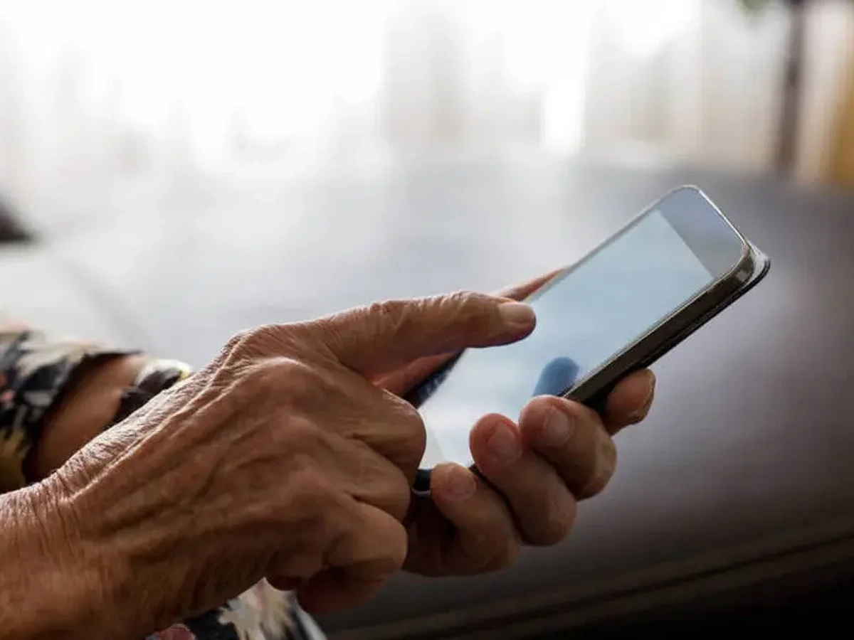 Pessoa idosa utilizando um celular durante curso de inclusão digital em Anápolis.