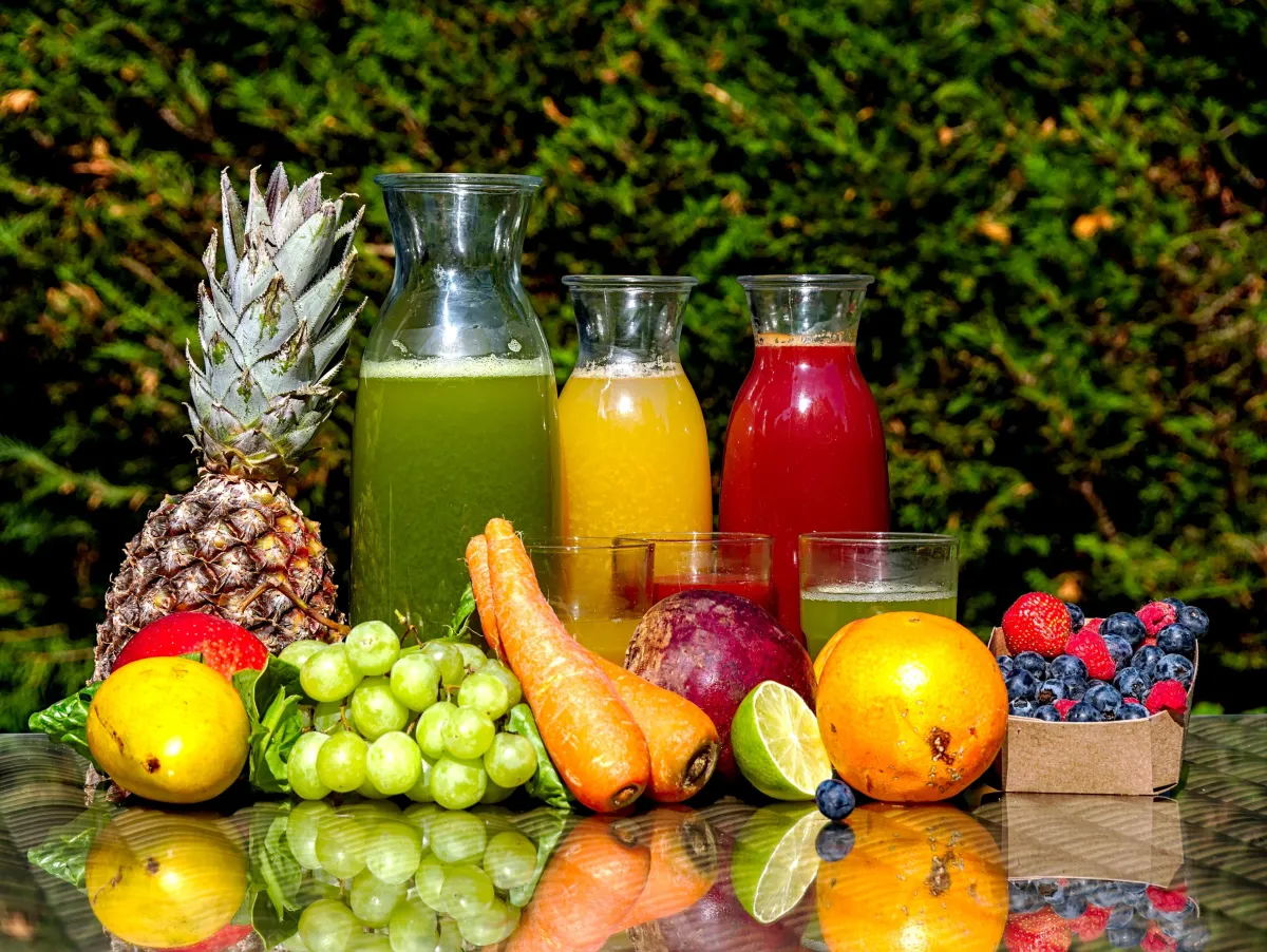 Sucos naturais acompanhados de frutas e vegetais sobre uma mesa. Foto: Zlatko Đurić/Unsplash.