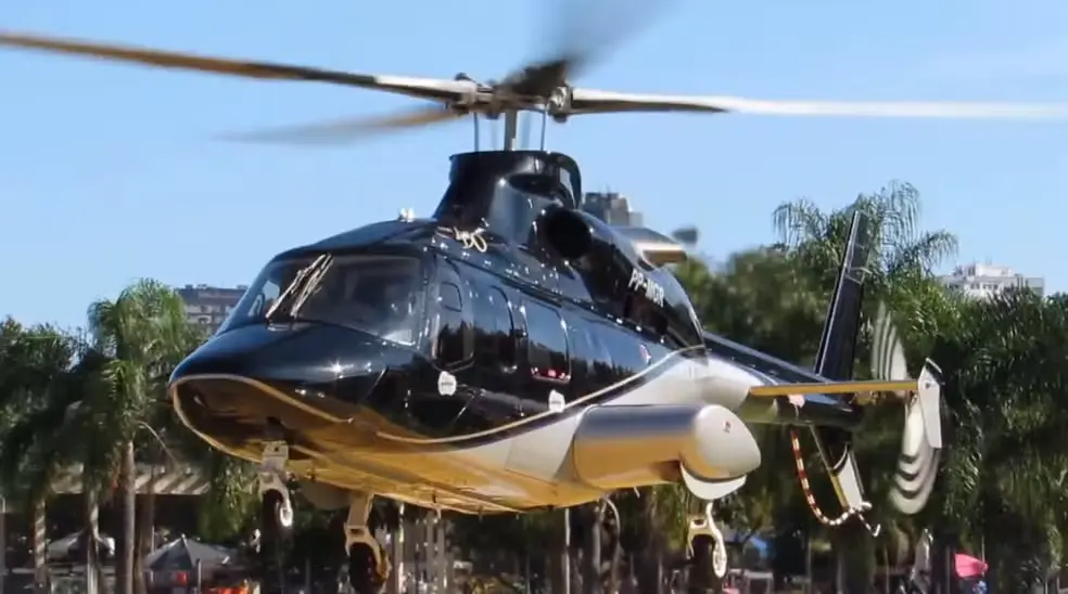 Helicóptero preto e branco, com detalhes dourados, fotografado durante um voo.