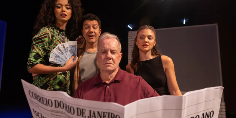 Cena da peça “Baixa Sociedade” mostra quatro atores no palco, com dinheiro e jornal em destaque.