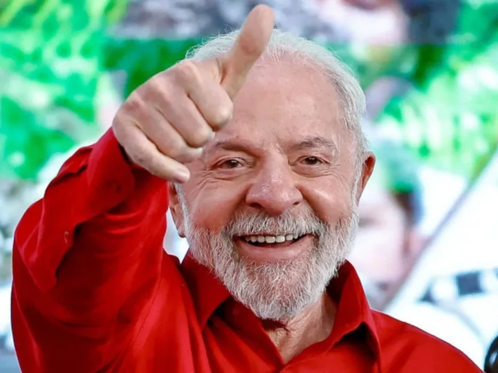 Lula sorri e levanta o polegar, usando camisa vermelha.