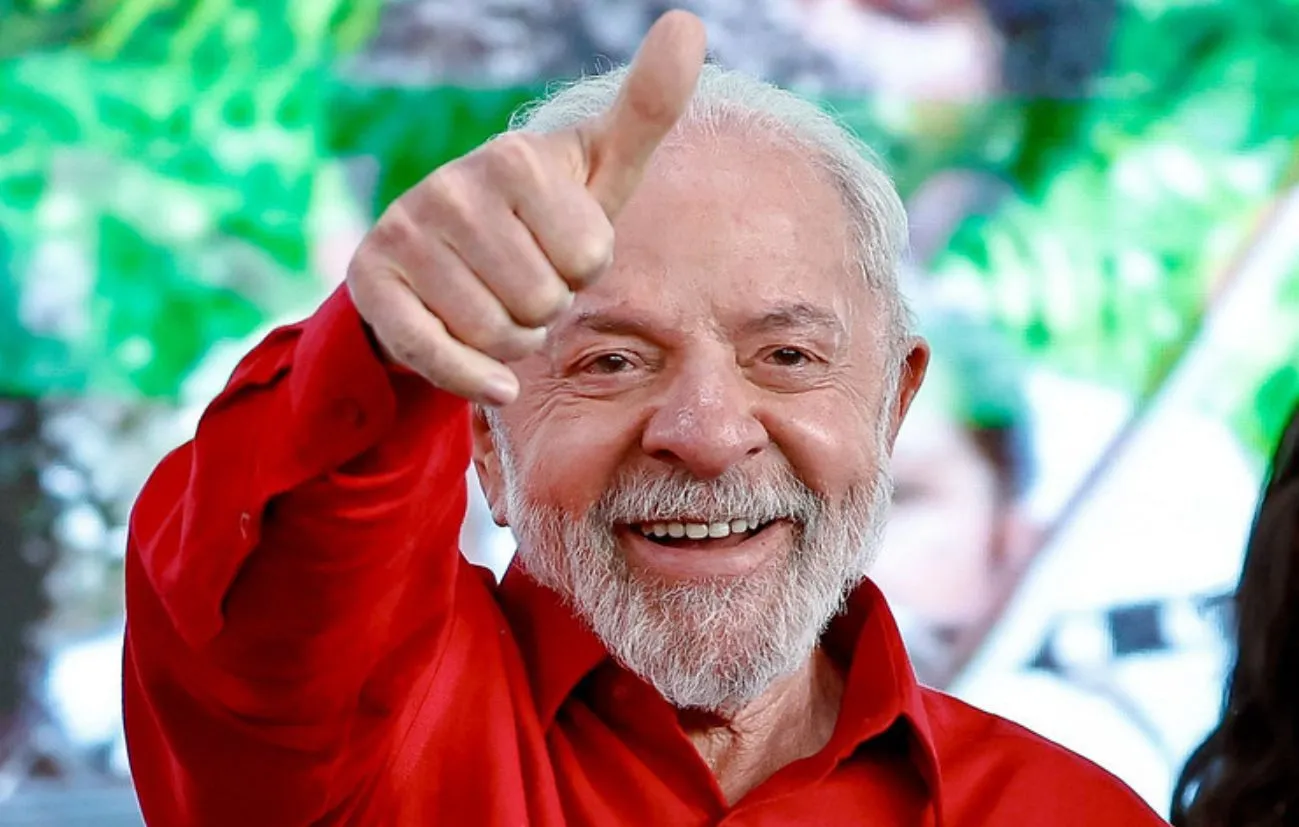Lula sorri e levanta o polegar, usando camisa vermelha.
