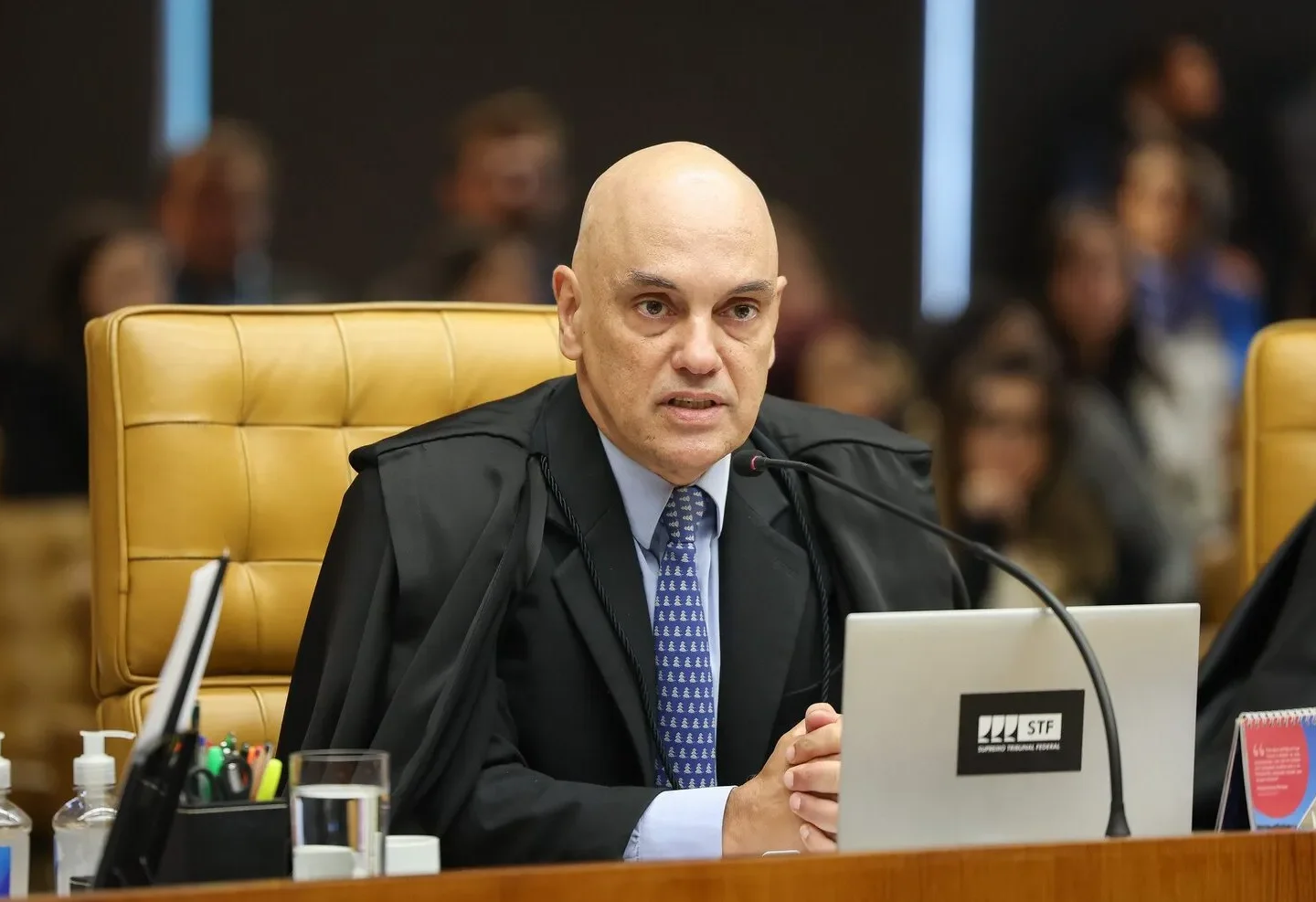 Alexandre de Moraes sentado no plenário do STF, diante de um microfone e de um notebook.