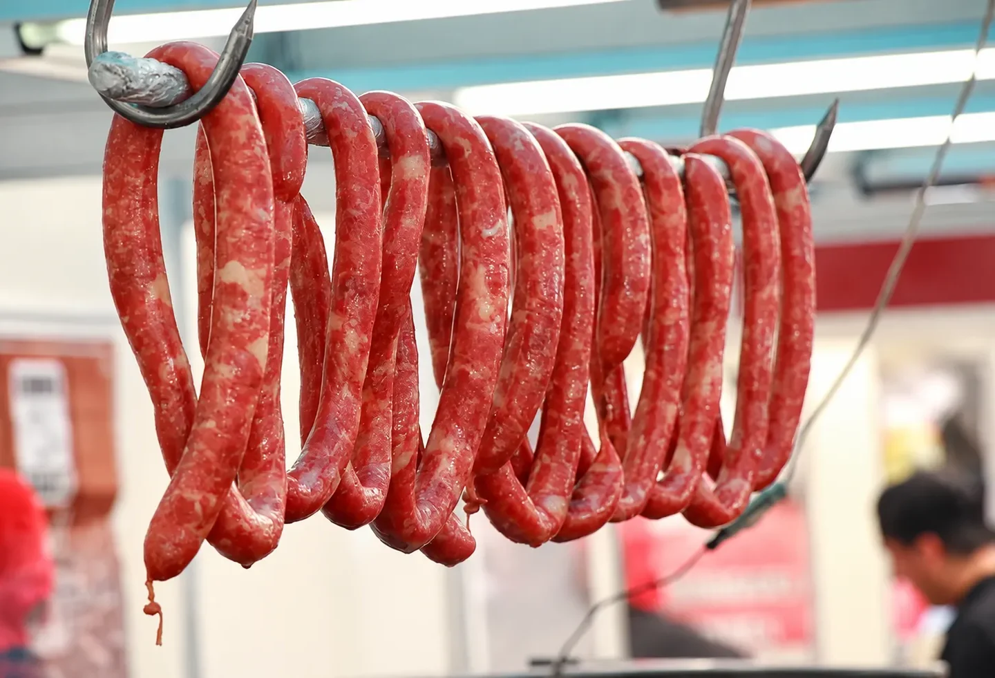 Linguiças penduradas em uma barra metálica em estabelecimento comercial. Imagem ilustrativa.