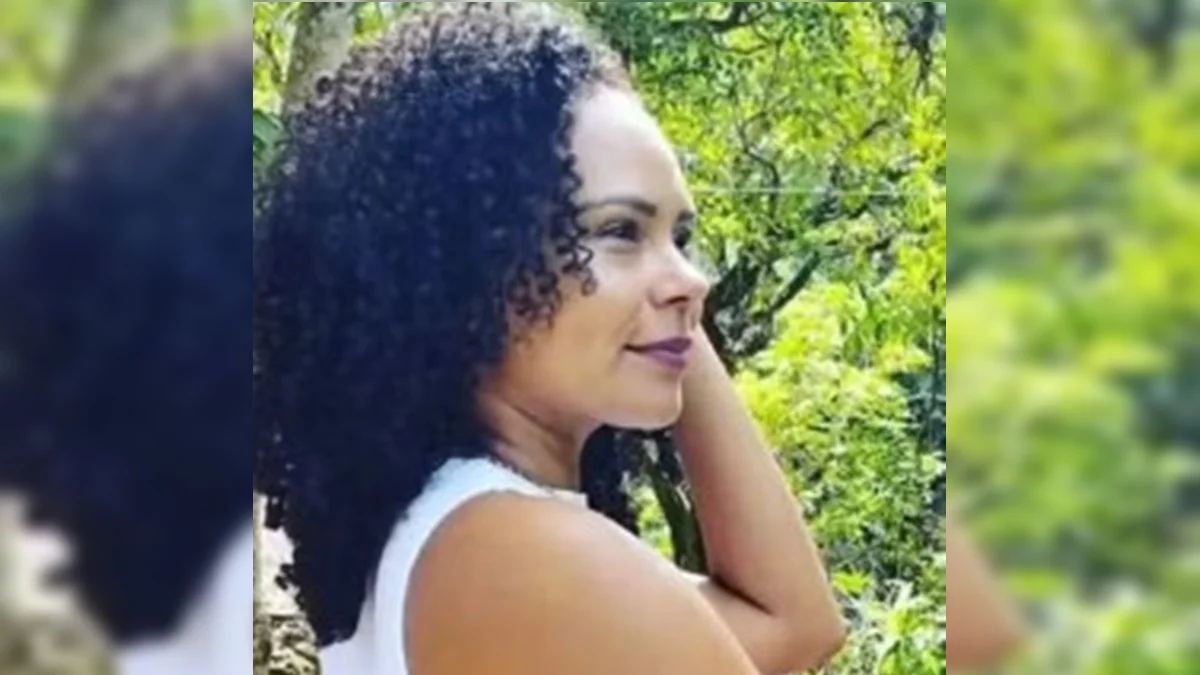 Juliana dos Santos Menezes posa de perfil, com blusa branca e árvores ao fundo.