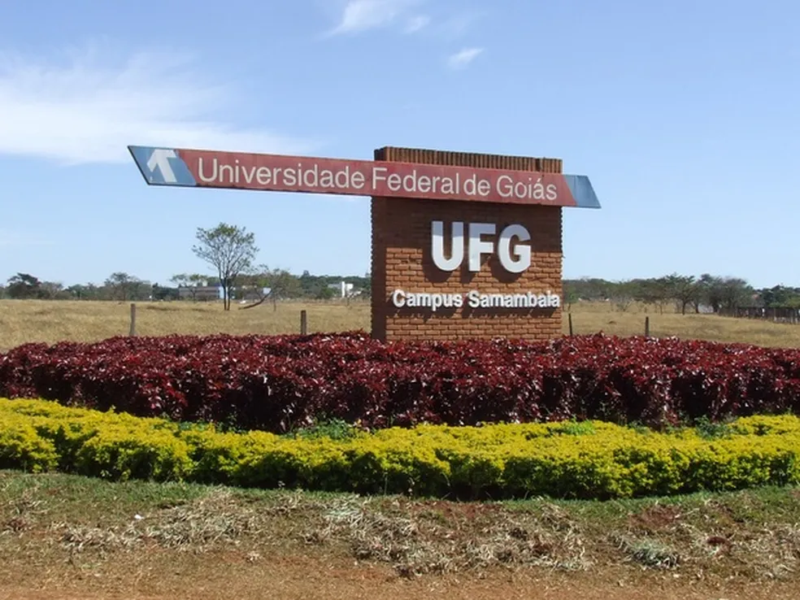 Placa de identificação do Campus Samambaia da Universidade Federal de Goiás, cercada por um jardim.